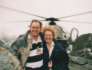 An old photograph of two people standing in front of a helicopter