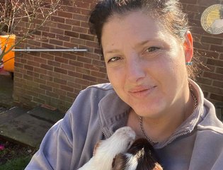 A woman standing in her garden cuddling guinea pigs