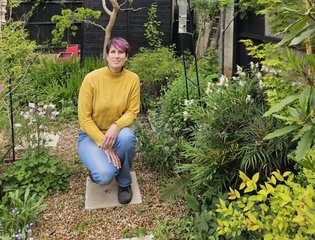 A woman standing proudly in her garden